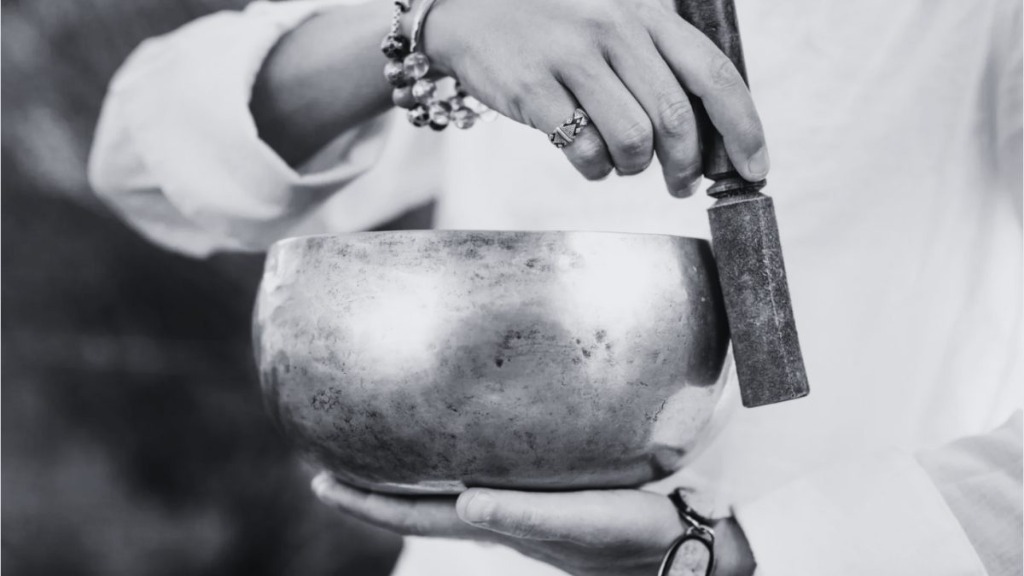 Hands holding and playing a sacred singing bowl for workplace clarity and focus
